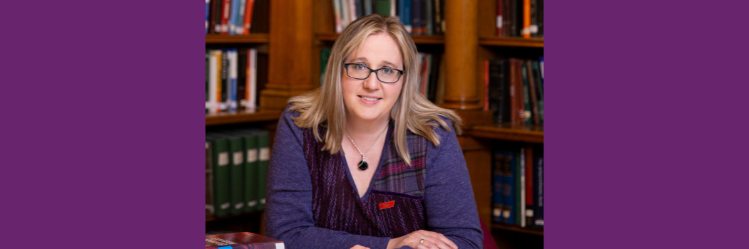 Dr Helen Meese sitting at a round table in an old library