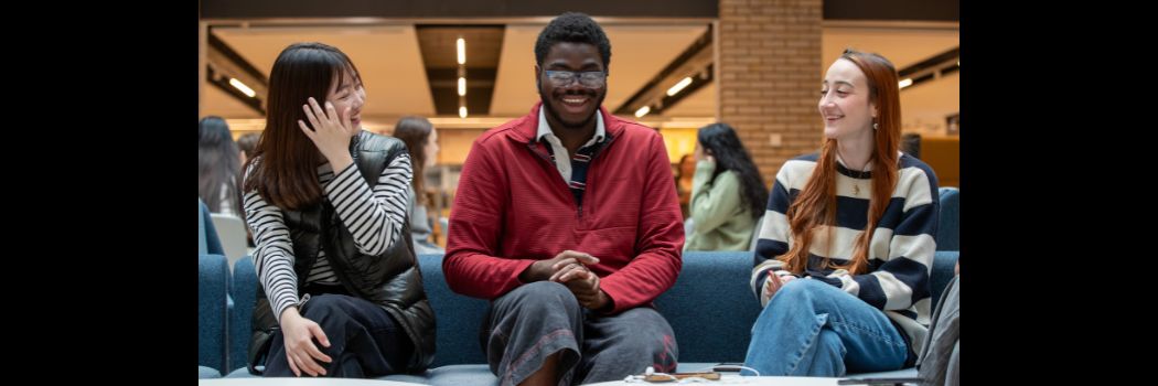 Three students sitting chatting and laughing