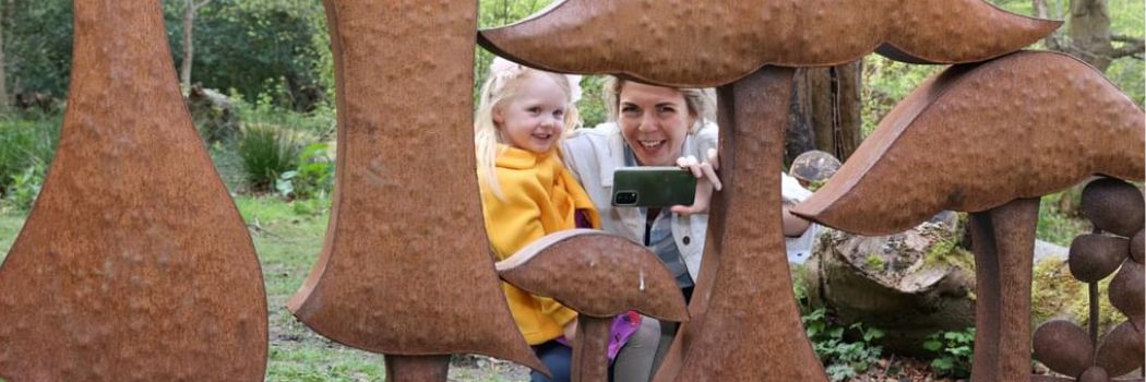 Woman child crouching behind mushroom sculpture