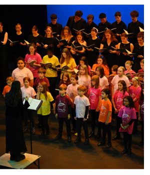 School children singing on a theatre stage