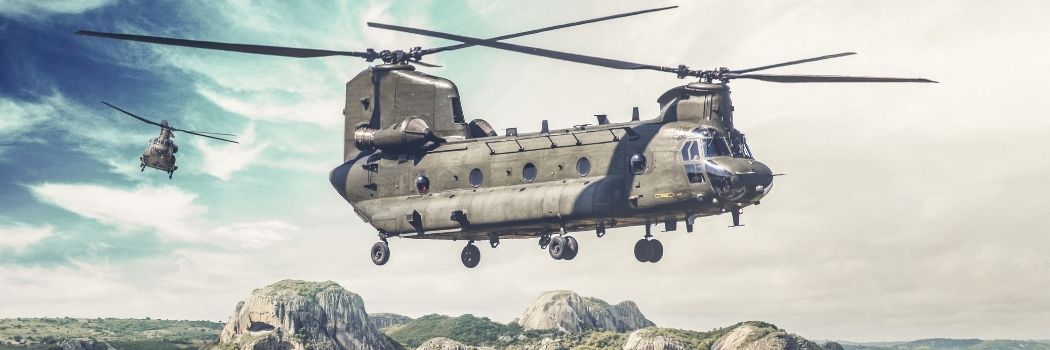 A US military helicopter flies over a green landscape