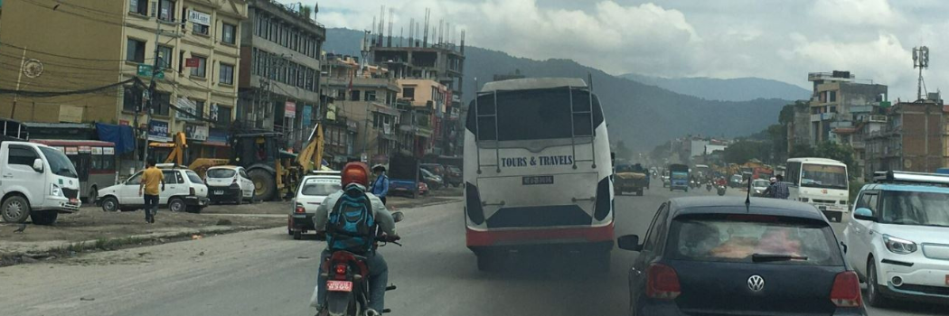 A road scene showing buses, cars and scooters emitting pollution