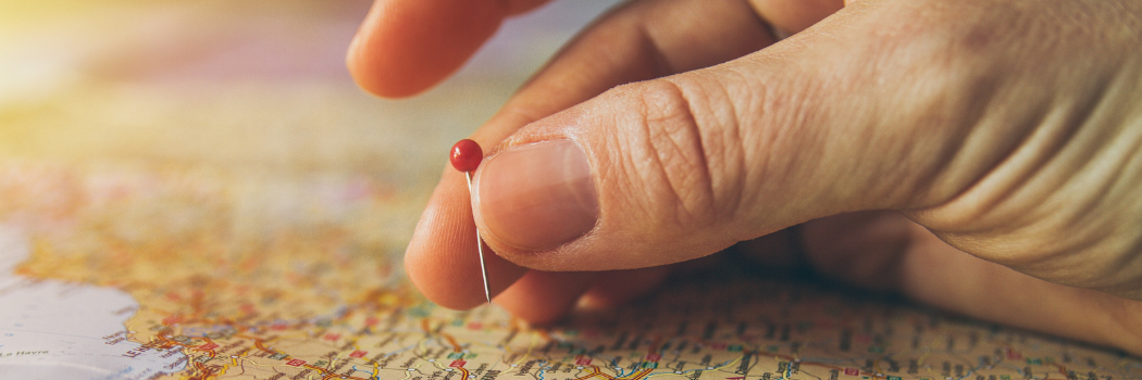 A hand placing a pin in a world map