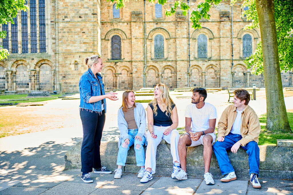 A group of students sat on a wall in front of the cathedral