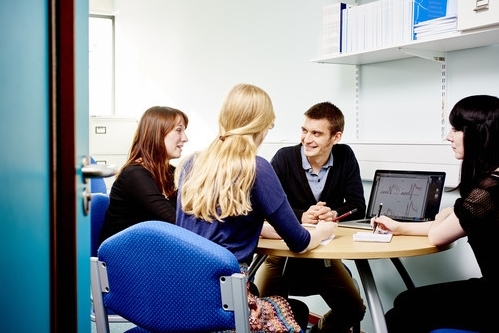 Academic lecturer meeting with postgraduate students in office