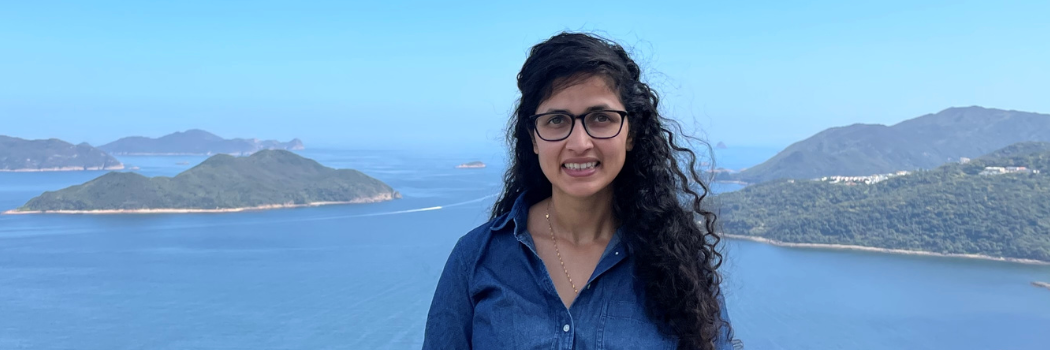 An image of Assistant Professor Renu Singh with the ocean and mountains in the background.