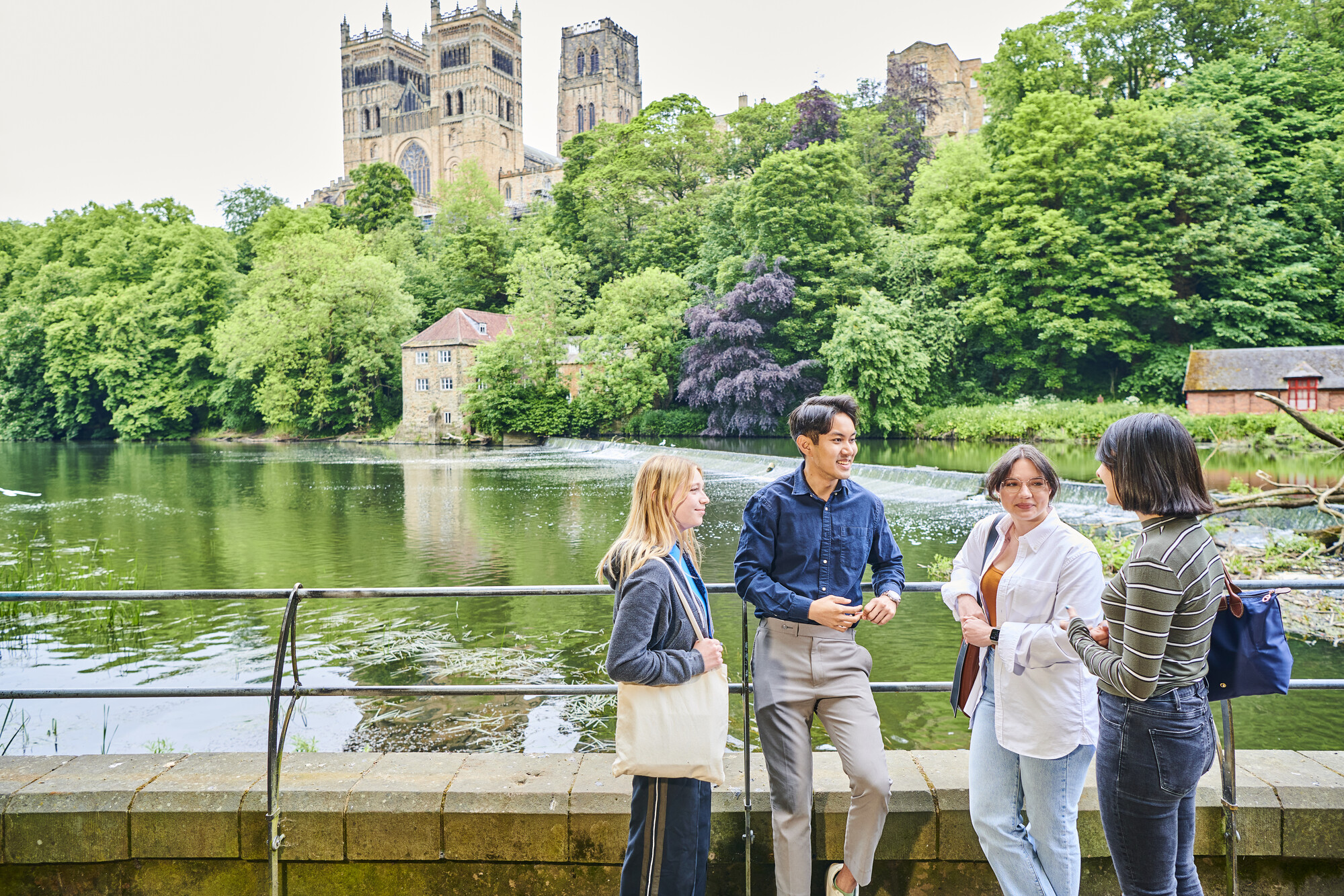 A group of students by a river in front of Durham Cathedral