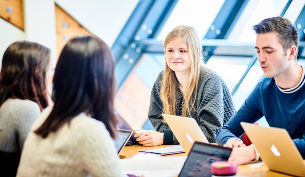 4 students around table with laptop