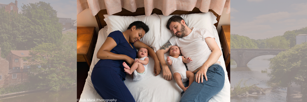 Parents lying next to babies in bed with durham underlay