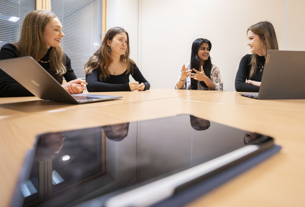 Four female students sitting and talking around a square desk