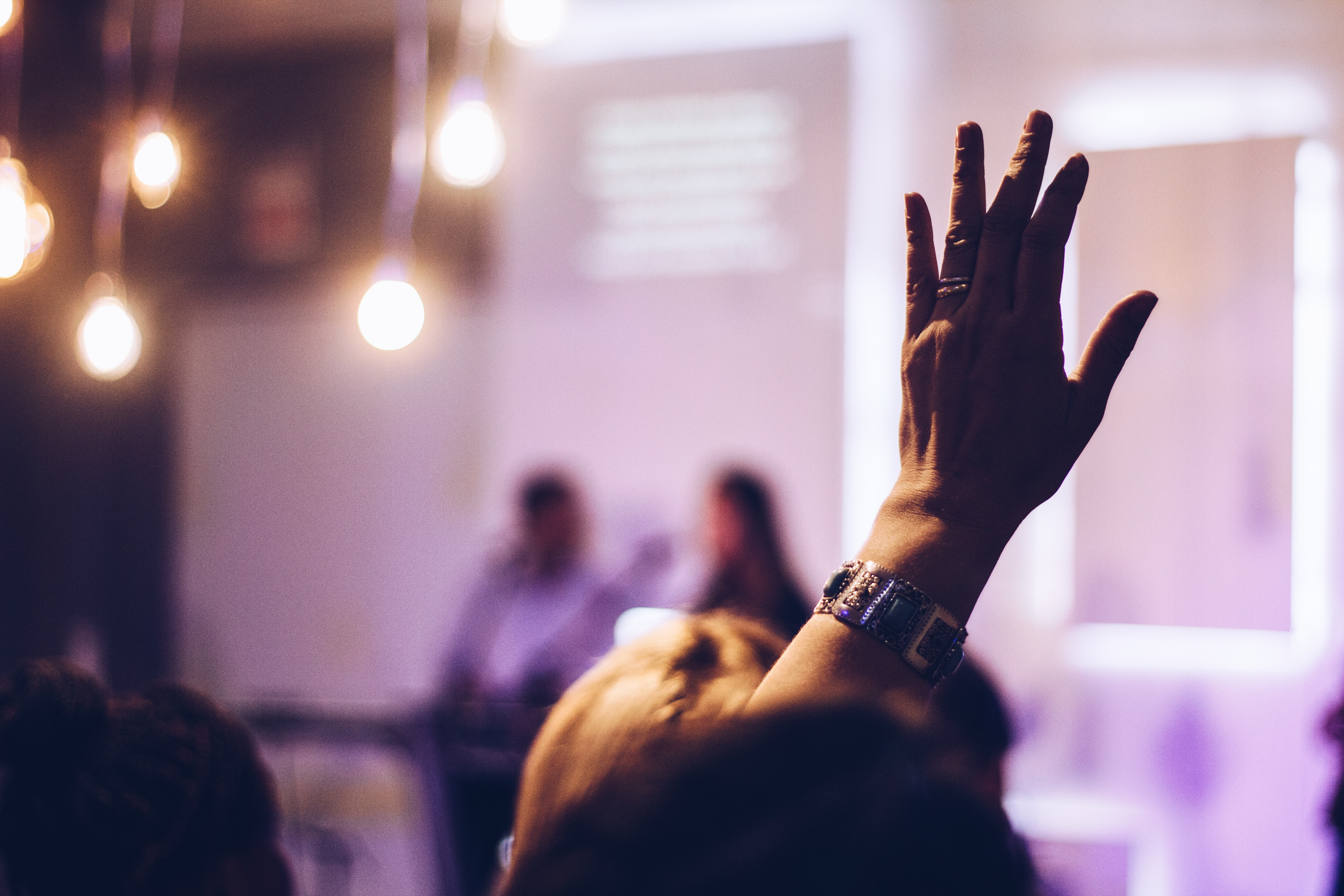 A woman with raised hand at a talk or seminar