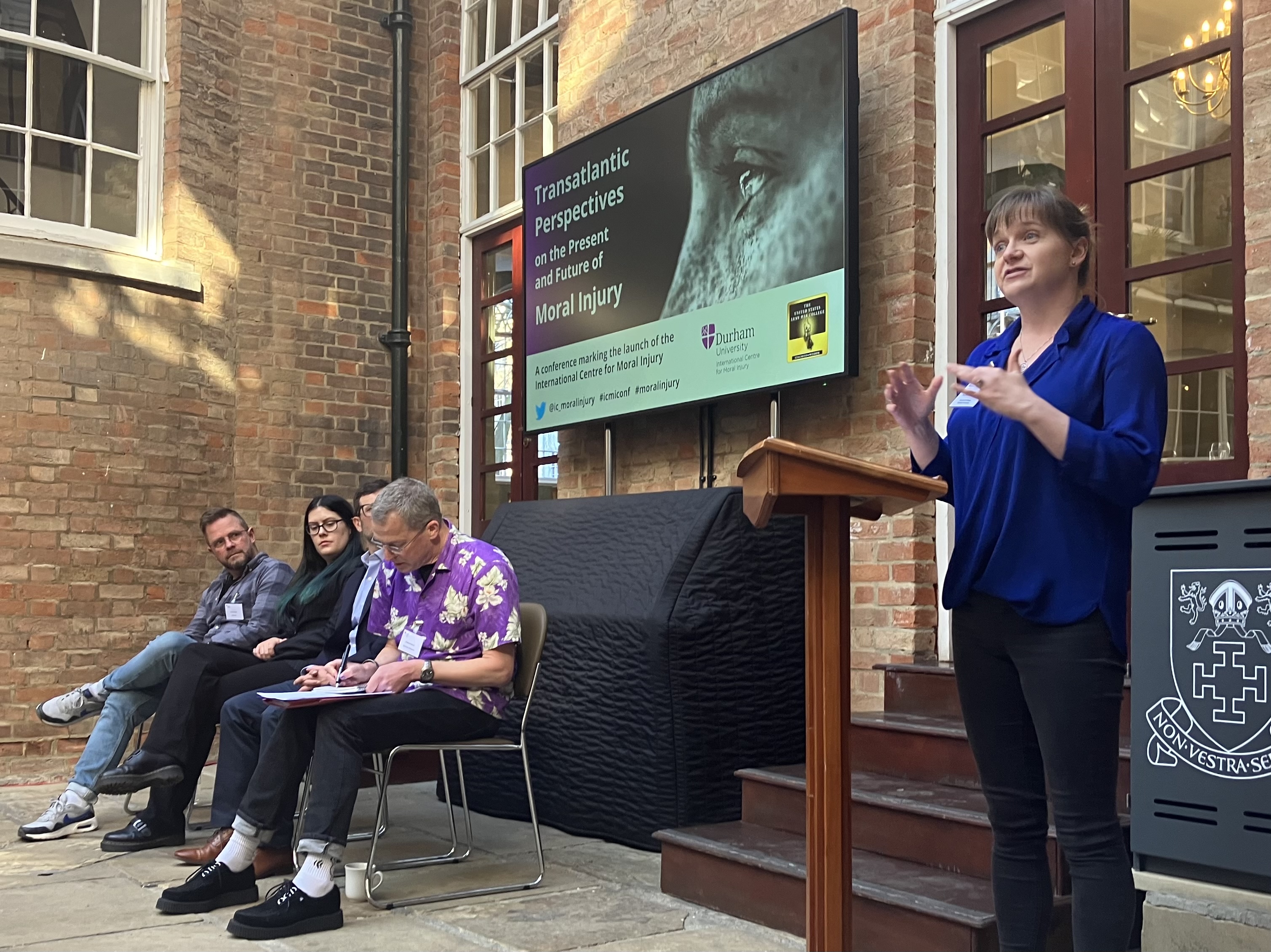 A lady at a lectern with a microphone reading a poem