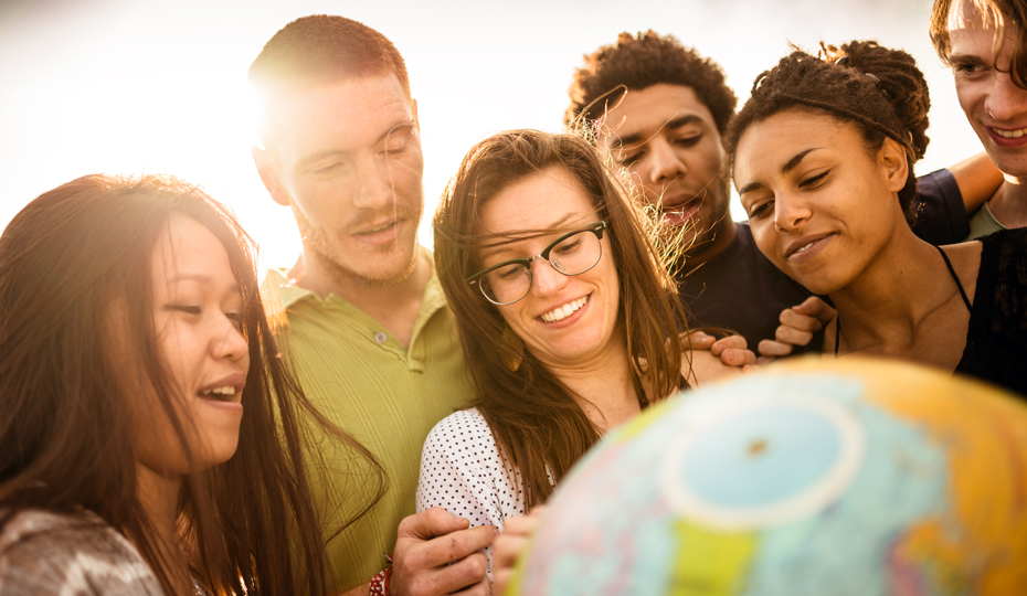 A group of students crowded around a world globe