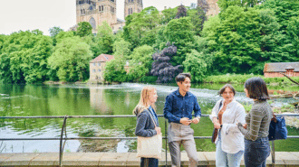 TFour students by the riverside with cathedral in the background